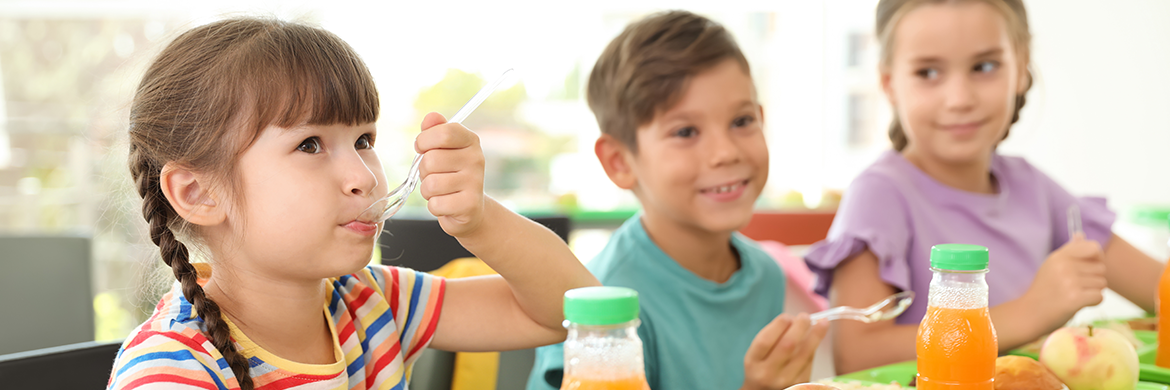 three children, two girls and a boy, eating lunch