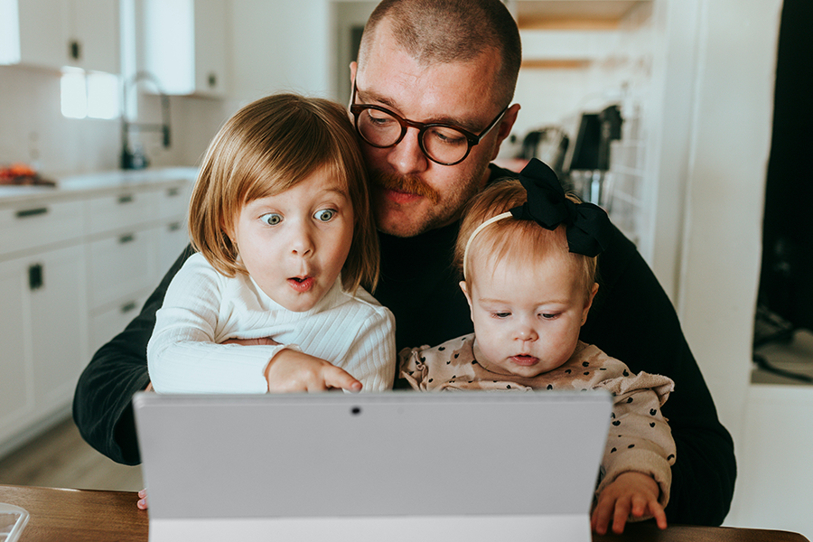 Dad with two infant daughters watching shows on a tablet