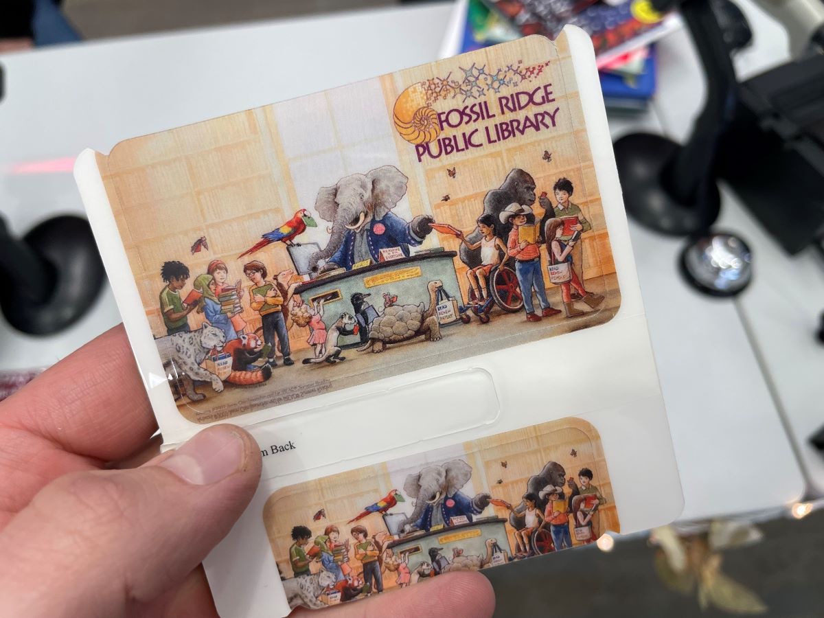 Person's hand holding new Fossil Ridge Public Library card