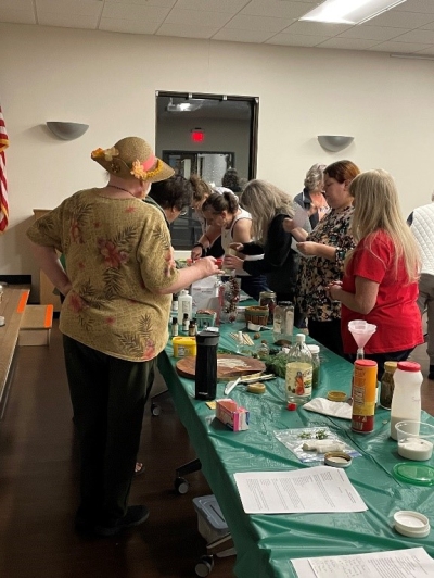 Adults gathered around tables covered in plastic and supplies for craftmaking